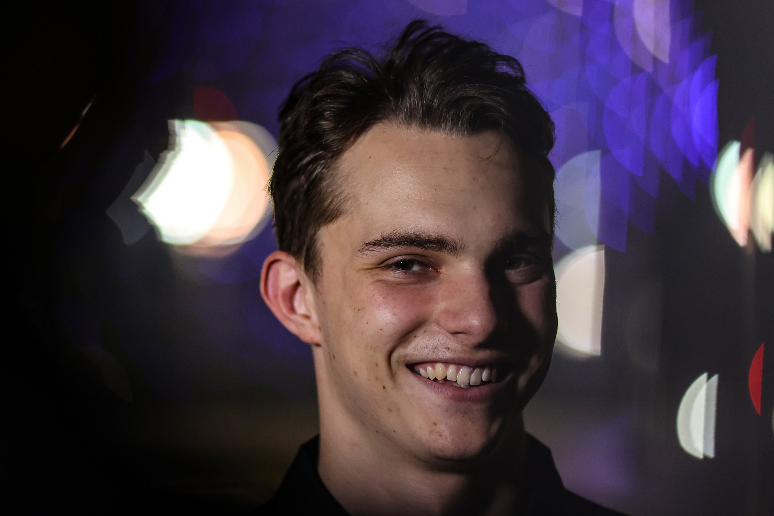 Oscar Piastri smiling in front of a dark background